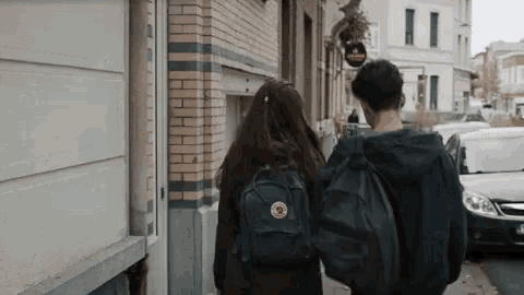 a man and a woman are walking down the street .