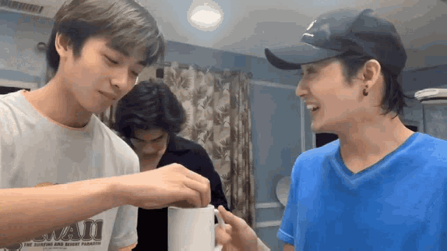 a man in a hawaii shirt is pouring something into another man 's mug