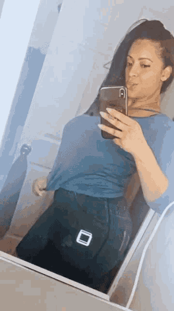 a woman is taking a picture of herself in a mirror with her phone .