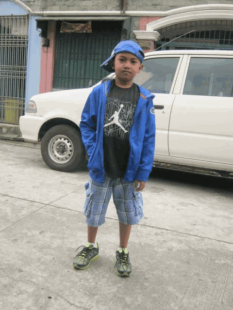 a young boy wearing a blue jacket and a jordan shirt stands in front of a white van