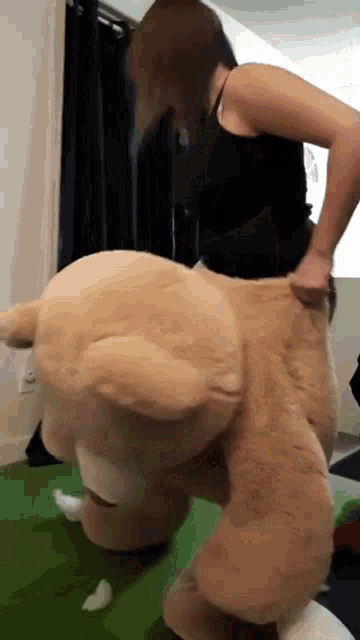 a woman is holding a large teddy bear on her back .