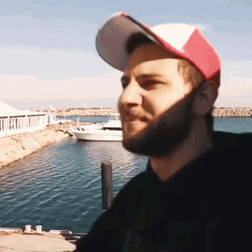 a man with a beard wearing a red and white baseball cap