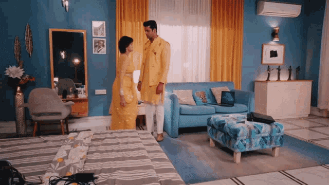 a man and woman are standing in a living room with a blue couch