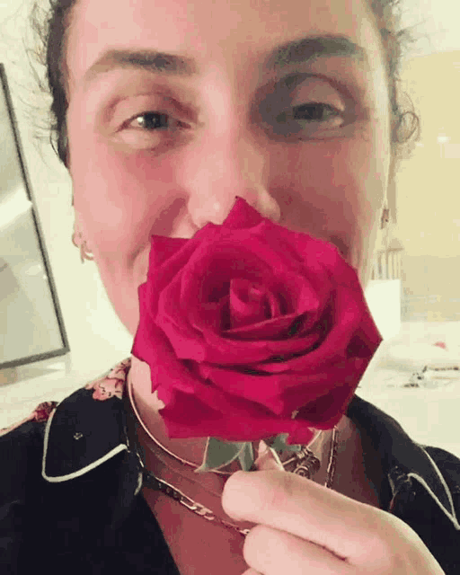 a woman is holding a red rose in her hand