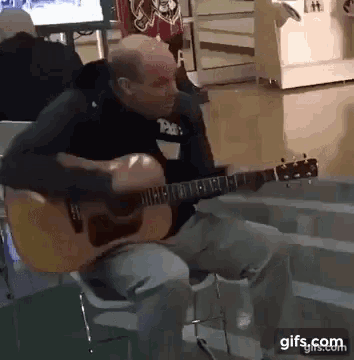 a man playing an acoustic guitar with a gifs.com watermark on the bottom
