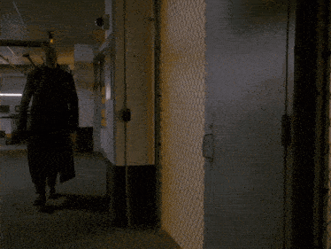 a man in a black coat is walking in front of a gate that says private