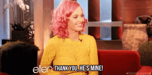 a woman with pink hair is sitting on a red couch and saying " thank you he 's mine "