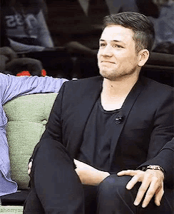 a man in a suit sits on a green couch