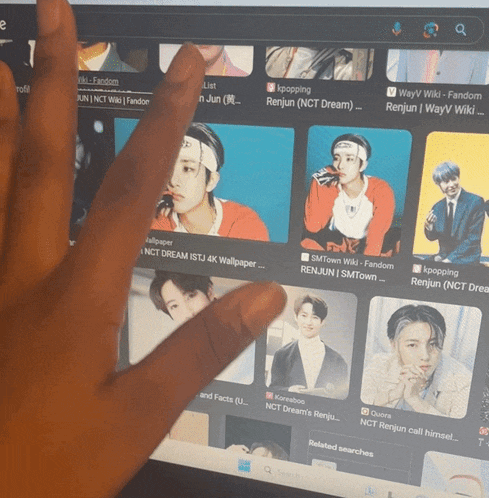 a person 's hand is pointing at a screen with pictures of renjun