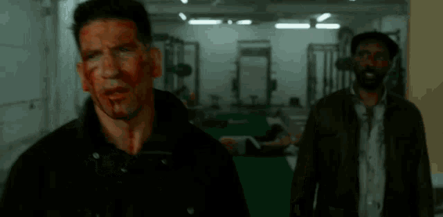 a man with blood on his face is standing next to another man .