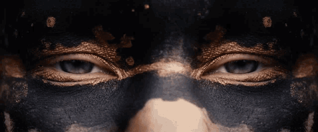 a close up of a person 's face painted black and gold