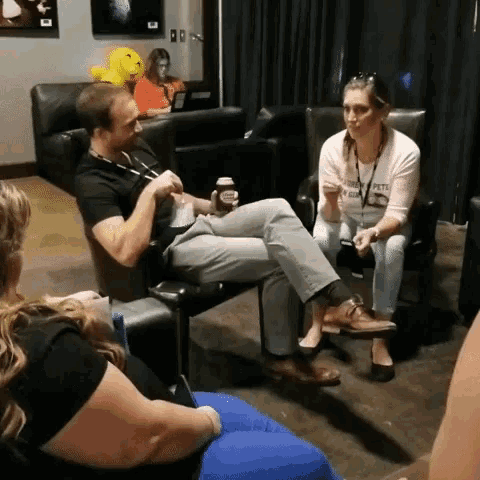 a man sitting in a chair talking to a woman who is wearing a shirt that says ' peter ' on it