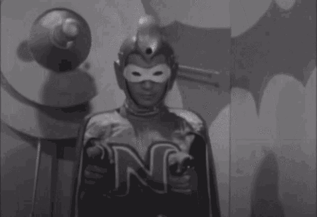 a black and white photo of a man in a superhero costume holding a light .