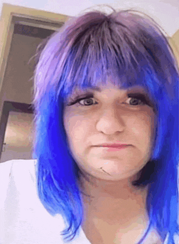 a woman with blue and purple hair is making a face