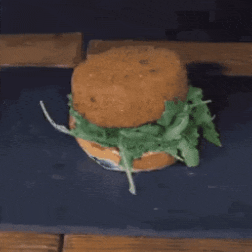 a close up of a person cutting a hamburger with a knife on a table .