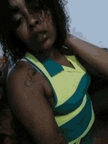 a woman with curly hair is wearing a yellow and green striped top