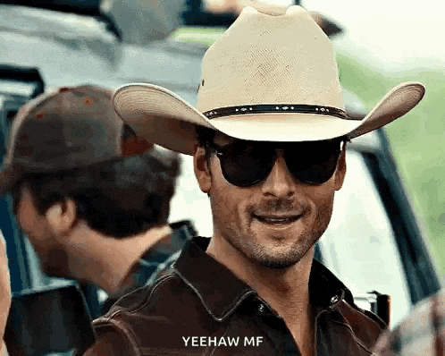 a man wearing a cowboy hat and sunglasses is smiling and says yeehaw mf .