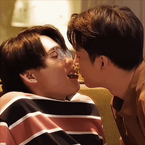 two men kissing with one wearing glasses on