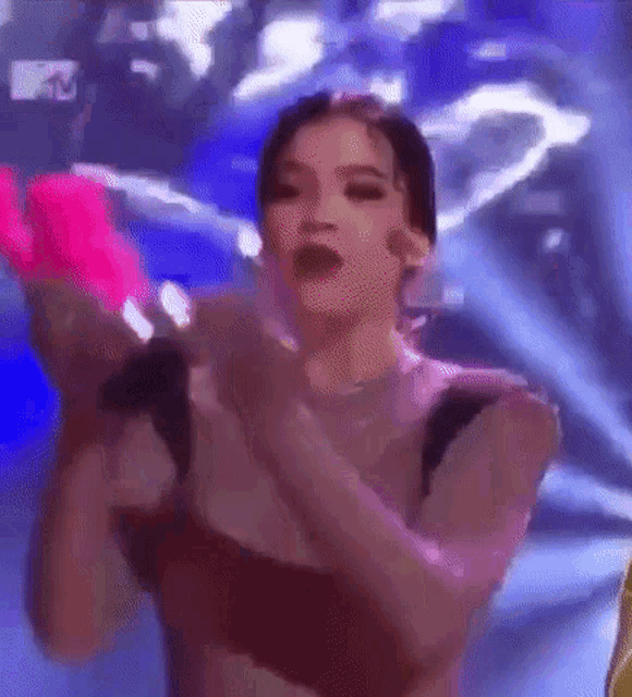 a woman is standing on a stage holding a pink object .