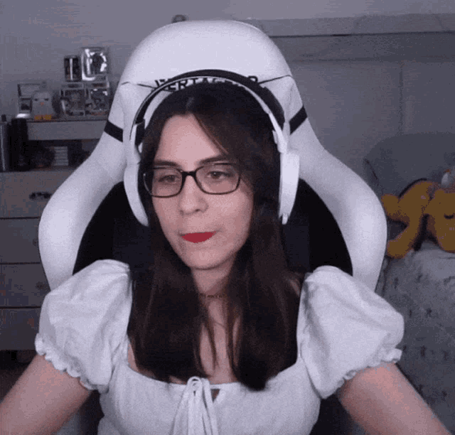 a woman wearing glasses and headphones sits in a chair