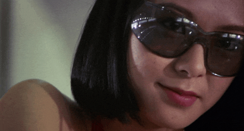 a close up of a woman wearing sunglasses and a red top
