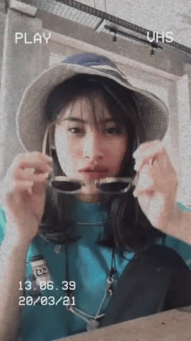 a woman wearing a hat and sunglasses has a play button on the bottom right