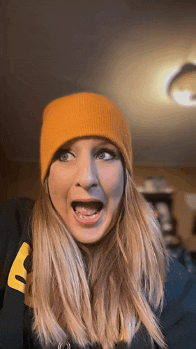 a woman wearing a yellow beanie and a black sweatshirt with the letter a on it