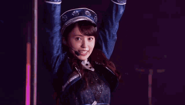 a woman wearing a hat and a microphone is dancing with her arms outstretched