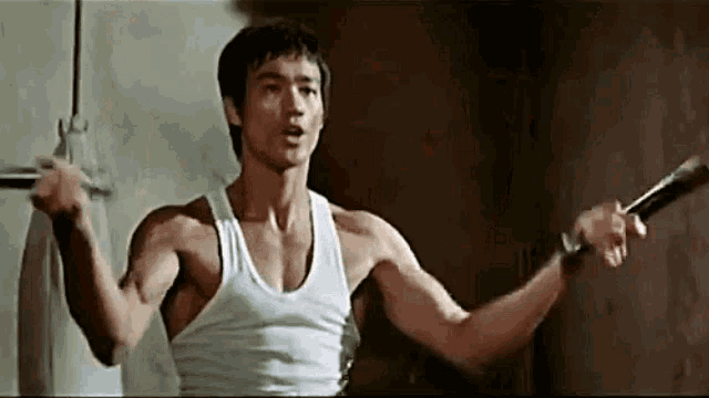 a man in a white tank top is holding a sword in his hands .