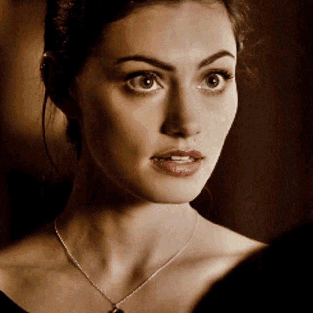 a close up of a woman wearing a necklace with a pendant