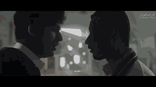 two men are looking into each other 's eyes with arabic writing on the bottom right corner