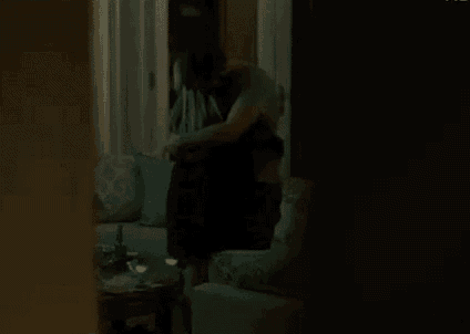 a man is hugging a woman in a living room .