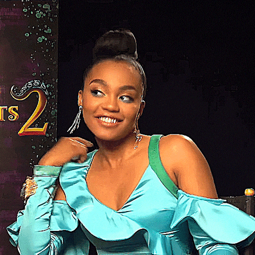 a woman in a blue dress is smiling in front of a sign with the number 2 on it