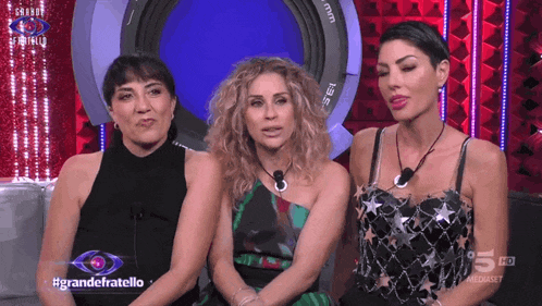 three women sitting in front of a camera with the words grandefratello on the screen