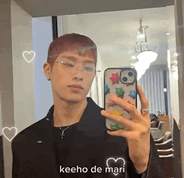 a man is taking a selfie in front of a mirror with his cell phone .