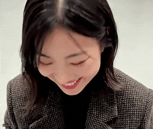 a close up of a woman wearing a plaid jacket and smiling