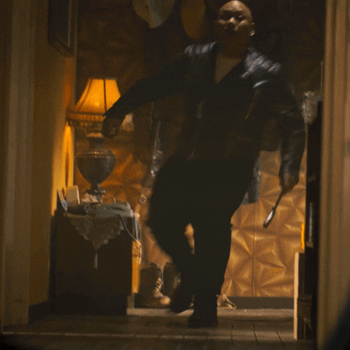 a man in a black leather jacket is standing in a dark room