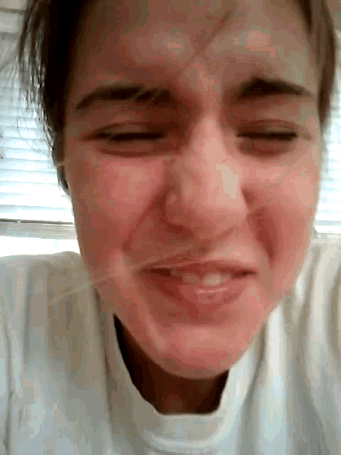 a close up of a woman 's face with a white shirt on