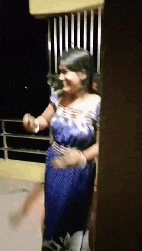 a woman in a blue dress is dancing on a balcony at night