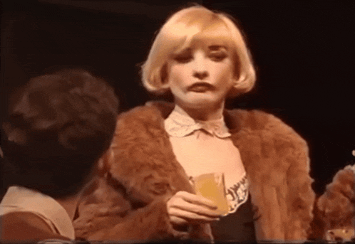 a woman in a fur coat holds a glass of orange juice
