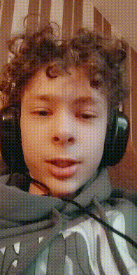 a young boy with curly hair is wearing headphones and a microphone around his neck .