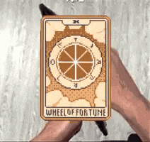 a person is holding a wheel of fortune tarot card .