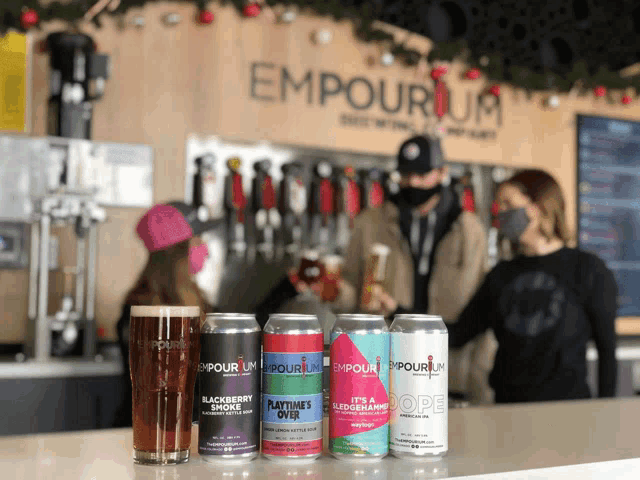 several cans of emporium beer are lined up on a bar