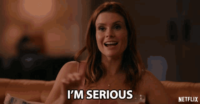 a woman says i 'm serious while holding a glass