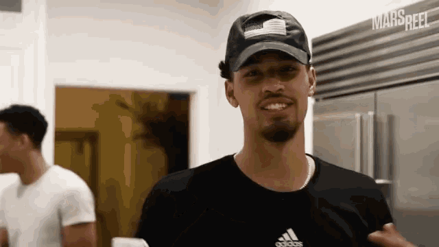 a man wearing a hat with an american flag on it and an adidas shirt