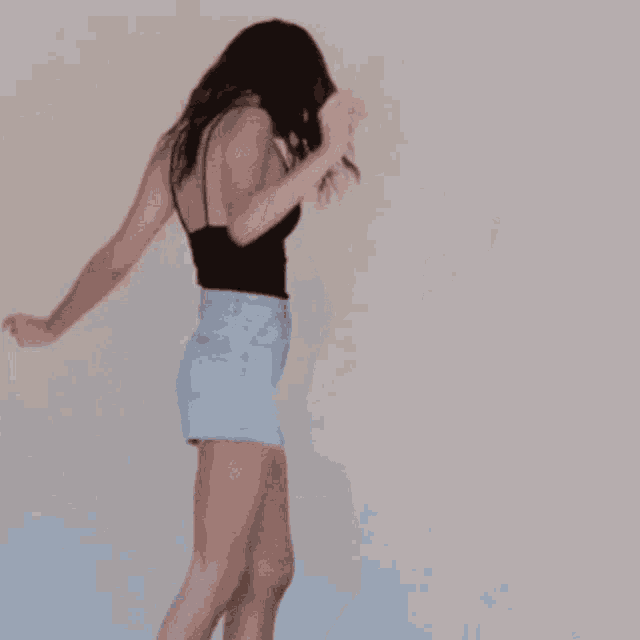 a woman wearing a black tank top and blue shorts is dancing
