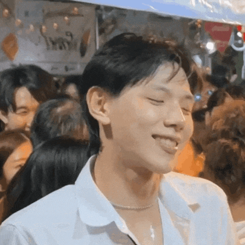 a young man is smiling in a crowd of people .