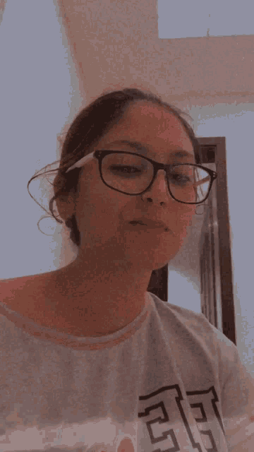 a woman wearing glasses is holding a piece of chocolate in her hand