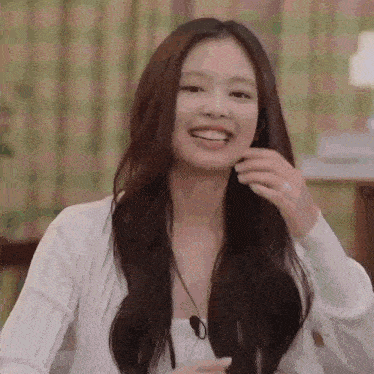 a woman with long hair is smiling while sitting on a couch in a living room .