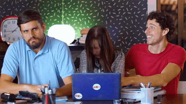 a group of people sitting at a table with a laptop that says or on it